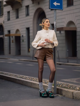 a lady wears a brown leather A-line shorts with a cropped jacket